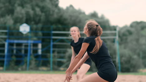 Young-woman-playing-volleyball-on-the-beach-in-a-team-carrying-out-an-attack-hitting-the-ball.-Girl-in-slow-motion-hits-the-ball-and-carry-out-an-attack-through-the-net.